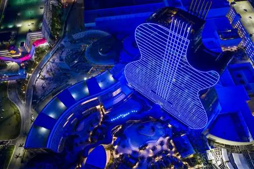 Аэрофотоснимок отеля и казино Seminole Hard Rock Hotel & Casino в форме гитары, освещенного синим светом ночью, Семинол, Флорида, США.