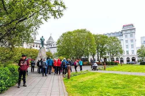 Улица в центре города со статуей Сигурдссона в парке Аустурволлур и туристической группой