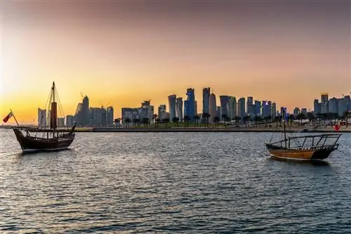 Парусники в море у зданий на фоне неба во время заката Парусники в море у зданий на фоне неба во время заката