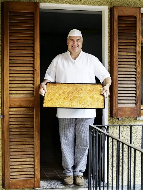 Пекарь держит поднос с печеньем fugascina в ресторане Al Vecchio Fornaio Pasticcere в Мергоццо.