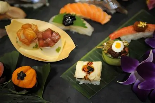 Изысканные композиции из суши и небольших тарелок расставлены на листьях и в бамбуковых контейнерах.