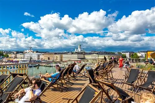 Люди отдыхают на солнышке на террасе у воды в Хельсинки.