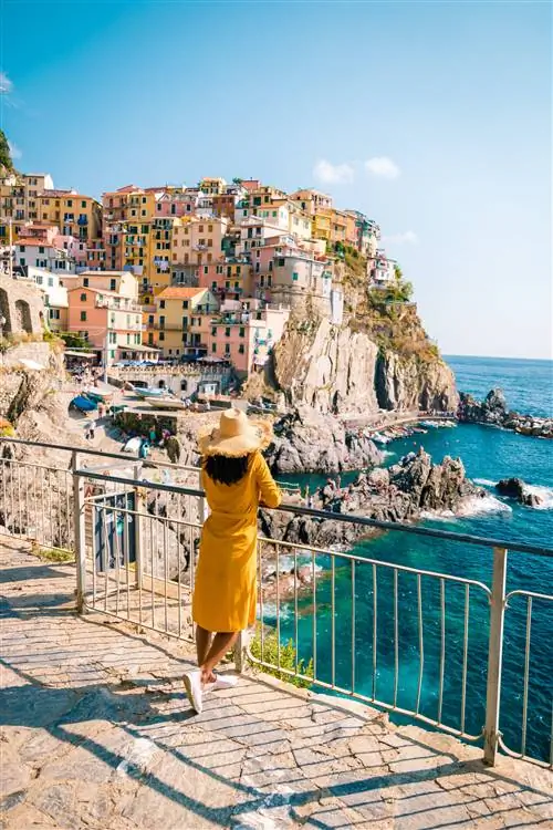 Женщина стоит перед красивой деревней Чинкве-Терре.