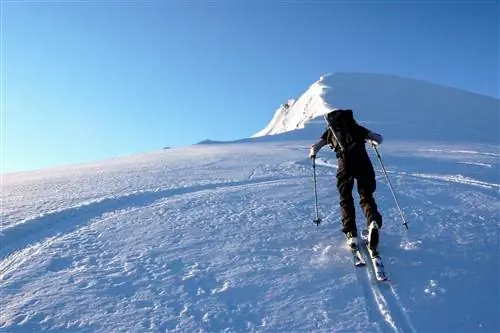 Одинокий лыжник-мужчина поднимается на гору возле Вильдхауса в горах Чурфирстен в Альпах в Швейцарии зимой в прекрасный ясный день.