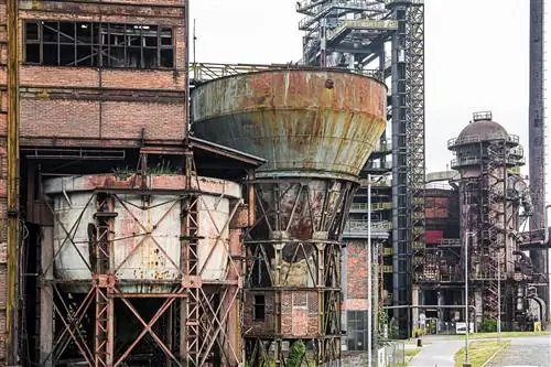 Промышленная архитектура, покрытая красной ржавчиной и явно заброшенная, включая бункеры, склады и башни.