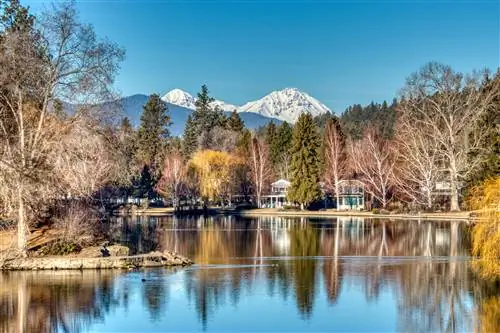 Вид на дома вокруг Зеркального пруда со снежными горами вдалеке в Бенде, штат Орегон, Тихоокеанский северо-запад, США.