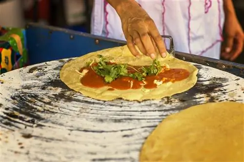 Рука шеф-повара готовит кесадилью с желтой молью (крот амарилло) из мексиканского штата Оахака.