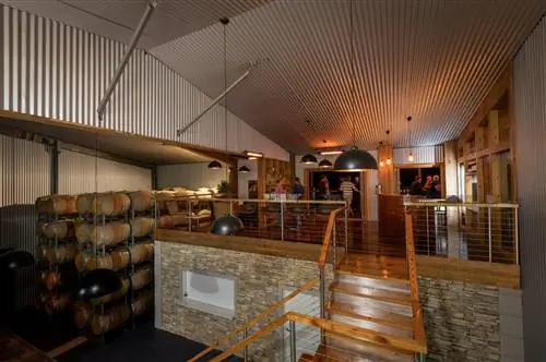Интерьер винодельни Aztes Corner Wines, напоминающий склад, в долине Баросса. Бочки с вином сложены слева, а справа небольшой бар.