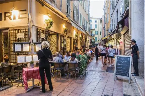Люди сидят возле ресторана вечером в Старой Ницце, Франция.