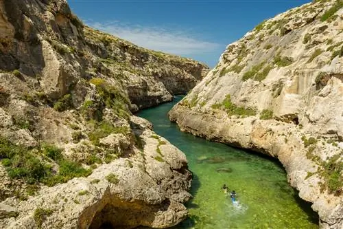 Вид-иль-Гасри на Мальте - это узкая «река» с морской водой, бегущая от моря к небольшому песчаному пляжу. На этом изображении двое ныряльщиков плывут по узкому проходу с крутыми скалами по обе стороны от них.