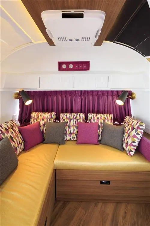 Красочный интерьер трейлера Zedstream Airstream в отеле Zed в Британской Колумбии украшен теплым деревом, желтыми виниловыми сиденьями и пурпурными шторами, которые гармонируют с подушками, обитыми розовыми, зелеными, фиолетовыми и белыми узорами арлекина.
