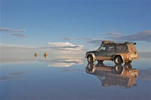 4WD стоит на мелководье, создавая почти идеальное отражение. Он находится на обширной плоской территории, которая, кажется, простирается бесконечно