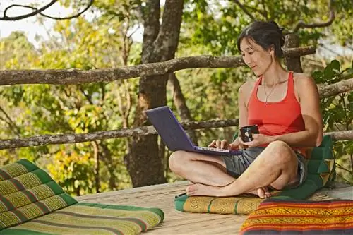 Женщина сидит со своим ноутбуком на открытой террасе