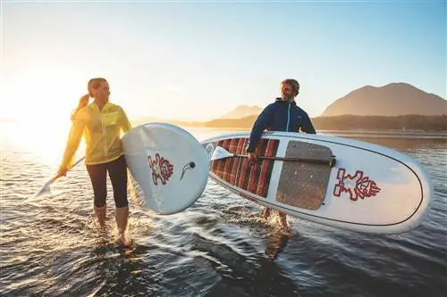 Два байдарочника выходят из прибоя со своими досками и веслами.