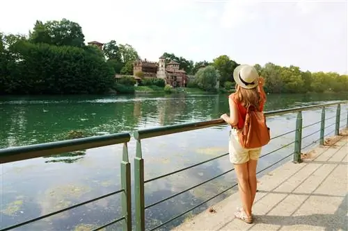 Женщина смотрит через реку По в Турине в Средневековом Борго.