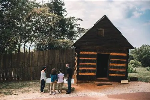 Семья смотрит на мемориальную доску перед деревянным зданием в Монтичелло.