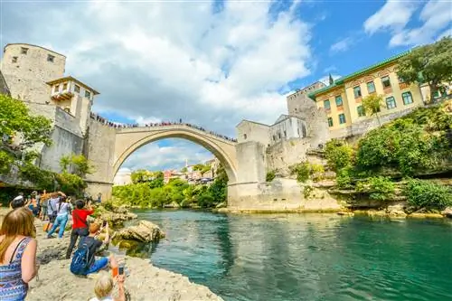 Туристы наблюдают, как смельчак ныряет в реку Неретва в Мостаре, Босния и Герцеговина.