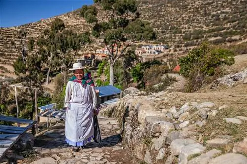 Женщина аймара идет по каменистой тропе на острове Исла-дель-Соль, озеро Титикака, Боливия.