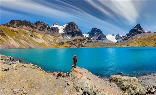 Путешественник в пончо смотрит на пик Кондорири в Кордильера-Реаль, Боливия.