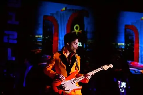 Принц выступает в отеле Rio в Лас-Вегасе, одетый в яркую оранжевую куртку и играющий на соответствующей оранжевой электрогитаре.