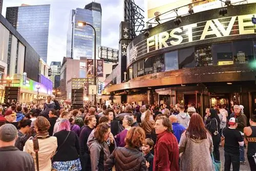 Музыкальное заведение на Первой авеню в Миннеаполисе: толпы людей стоят возле большого зала с надписью «Первая авеню» огромными золотыми буквами.