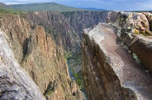 Узкая голубая лента воды прорезает высокие стены отвесной серой точечной скалы в Черном каньоне национального парка Ганнисон.