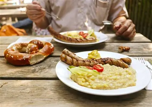 Большой крендель, жареные колбаски и картофельный салат, подается в баварском пивном саду.