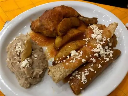 Белая тарелка с куриной ножкой, картофельными дольками, пышными рулетами и густым бежевым соусом. Белая тарелка с куриной ножкой, картофельными дольками, пышными рулетами и густым бежевым соусом.