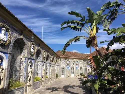 Внешний вид лиссабонского Дворца маркизов де Фронтейра; есть арки и мраморные статуи фигур, встроенные в стены, которые полностью покрыты замысловатой сине-белой расписной плиткой.