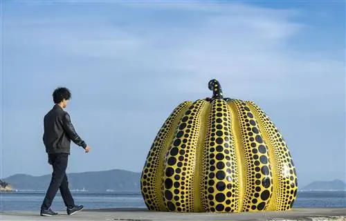 Японский турист приближается к желтой тыкве Кусамы на пирсе в Наосиме