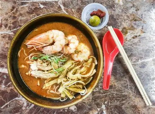 Чаша саравак лакши, вид сверху. Чаша наполнена густым бульоном с крупной лапшой, полосками куриного филе и креветками.