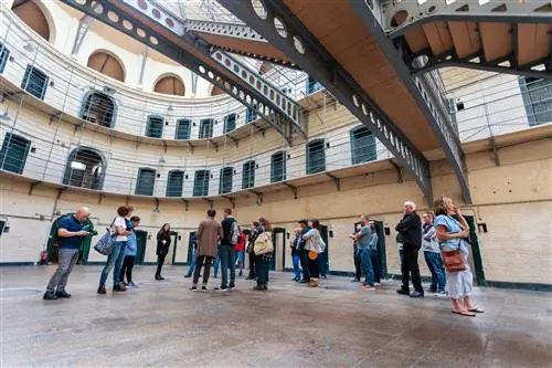 Экскурсионная группа стоит в большом зале тюремного корпуса в окружении дверей в отдельные камеры.