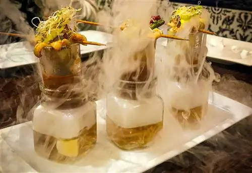 Шашлычки из морепродуктов балансируют на дымящихся стеклянных стаканах, которые напоминают пробирки, демонстрируя высокую гастрономию в ресторане в Кастилия-и-Леон, Испания.