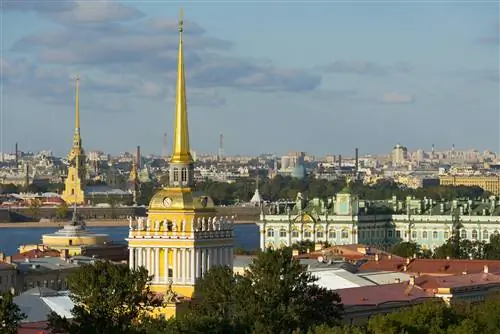 Вид с воздуха на знаменитую архитектуру Санкт-Петербурга с золотыми шпилями и богато украшенными фасадами, видимыми под голубым небом.