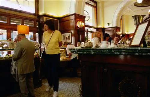 Женщина проходит мимо посетителей, потягивающих кофе в Caffè Gilli во Флоренции. Женщина проходит мимо посетителей, потягивающих кофе в Caffè Gilli во Флоренции.