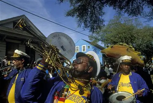 Группа мужчин, двое из которых играют на трубах, а другой играет на малом барабане, участвует в параде Мари Гра. Все в матросских шапках.