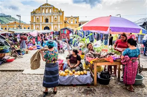 Продавцы рынка на оживленном воскресном рынке перед фасадом собора на главной площади Антигуа, Гватемала