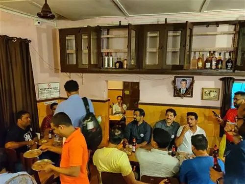 Посетители собираются в бело-охристом интерьере таверны Panjim, где высоко на стене висят шкафы из коричневого дерева с бутылками ликера.