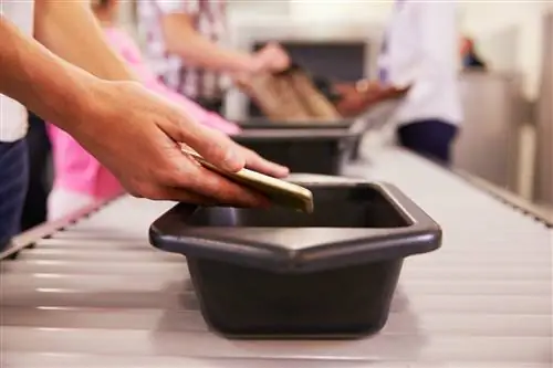 Мужчина положил мобильный телефон в лоток для досмотра в аэропорту