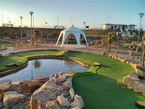 Водоем посреди поля на чемпионате Adventure Golf в Англии. В центре изображения виден навес.
