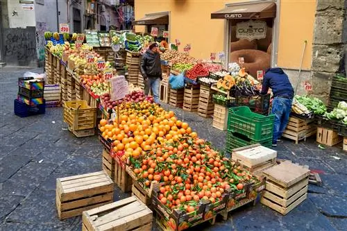 Крупный план апельсинов и других продуктов, сложенных высоко в овощном магазине в рыночном квартале Ла-Пиньясекка, Неаполь.