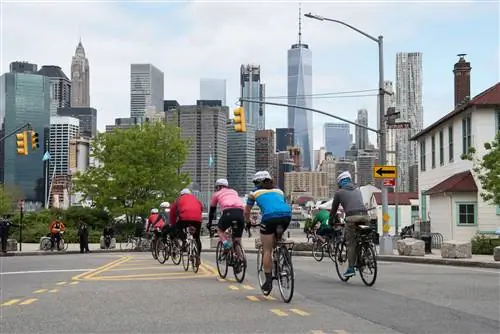 Велосипедисты едут на велосипеде Five Boro Bike Tour на фоне горизонта Манхэттена.