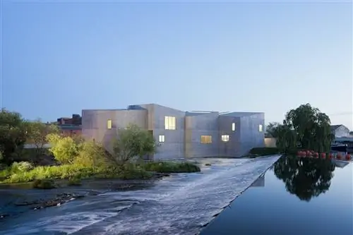Кадр минималистской блочной бетонной конструкции The Hepworth Wakefield; деревья смягчают суровый внешний вид, а стеклянная река течет по пологому склону рядом с галереей.