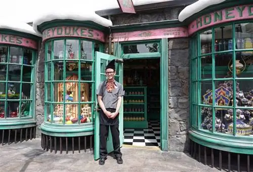 Костюмированный служитель стоит перед магазином Honey Dukes в Волшебном мире Гарри Поттера.