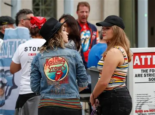 Пара женщин в черных джинсах и черных шляпах стоит возле Soldier Field в Чикаго перед концертом Rolling Stones. Одна стоит спиной к камере, на ней джинсовая куртка с вышитым на языке логотипом Rolling Stones и словами «Я знаю, что это всего лишь рок-н-ролл, но мне это нравится»