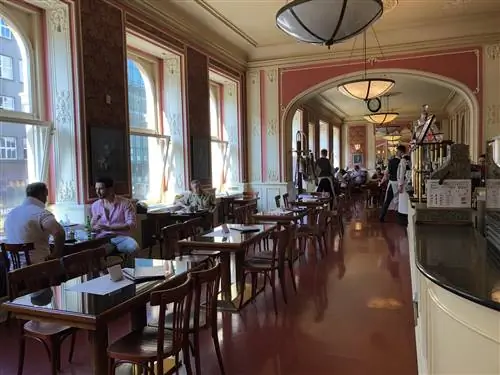 Посетители внутри Café Louvre с высокими потолками и украшениями в парижском стиле. Посетители внутри Café Louvre с высокими потолками и украшениями в парижском стиле.