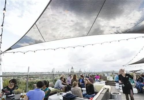 Посетители сидят снаружи в баре на крыше в SkyLounge, Амстердам, под облачным небом. Посетители сидят снаружи в баре на крыше в SkyLounge, Амстердам, под облачным небом.