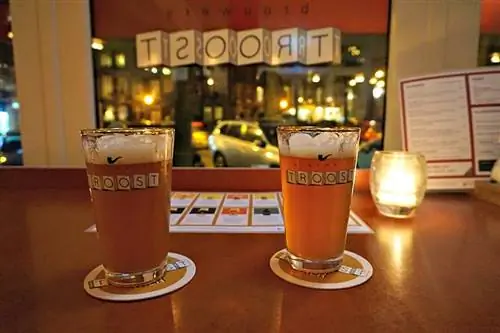 Две пинты пива освещены свечами вечером в Brouwerij Troost. Две пинты пива освещены свечами вечером в Brouwerij Troost.