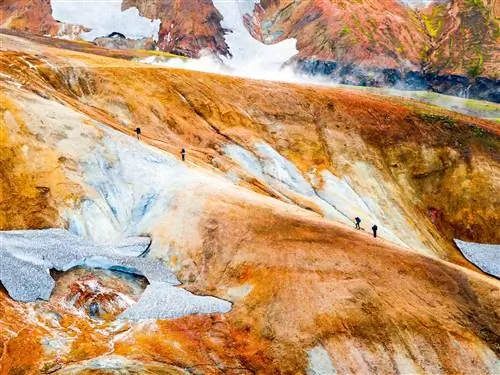 Четверо путешественников, разделенные на две группы по два человека, поднимаются по ржавому хребту, окруженному небольшими остатками ледников.