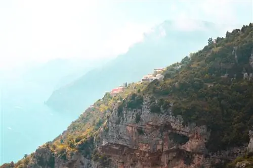 Фотография пешеходной тропы, известной как «Путь богов» в Италии. Терракотовые крыши почти видны на склоне поросшей лесом горы.